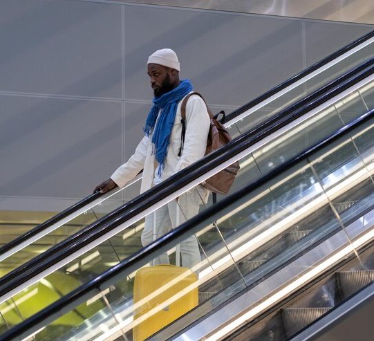 african-american-passenger-man-with-suitcase-stands-escalator-holds-handrail-airport-terminal_165285-7358