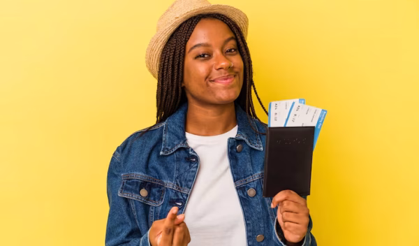 young-african-american-woman-holding-passport-isolated-yellow-background-pointing-with-finger-you-as-if-inviting-come-closer_1187-171116