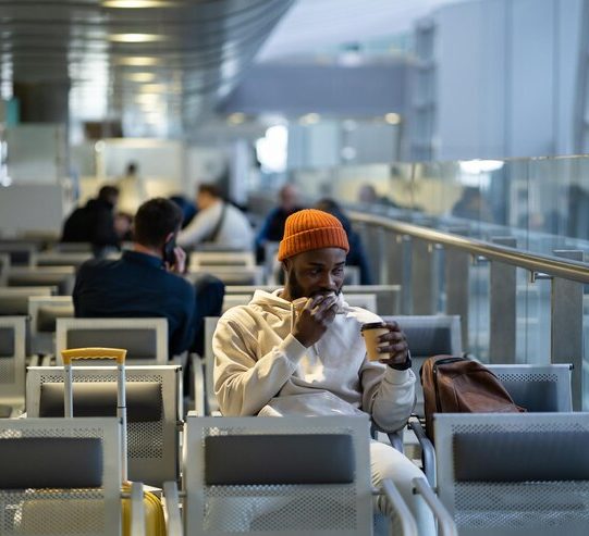 young-african-man-drinking-coffee-eating-sandwich-while-waiting-flying-airport-terminal_1048944-16561257